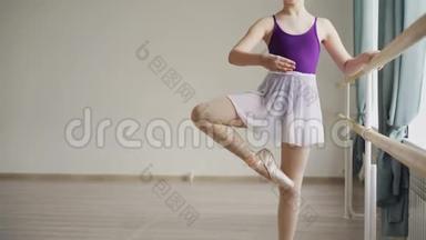穿着紧身衣和芭蕾舞裙的漂亮小女孩正在单独练习芭蕾，学习动作和姿势